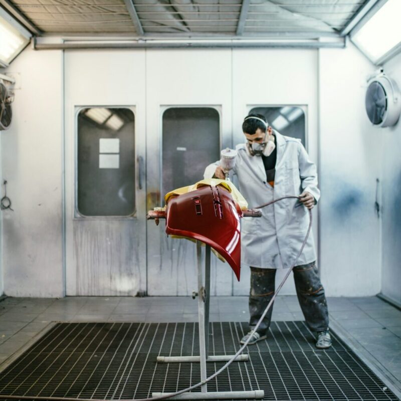 Man in paint booth spraying car parts